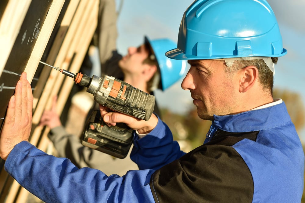 Construction worker using electric drill on building site