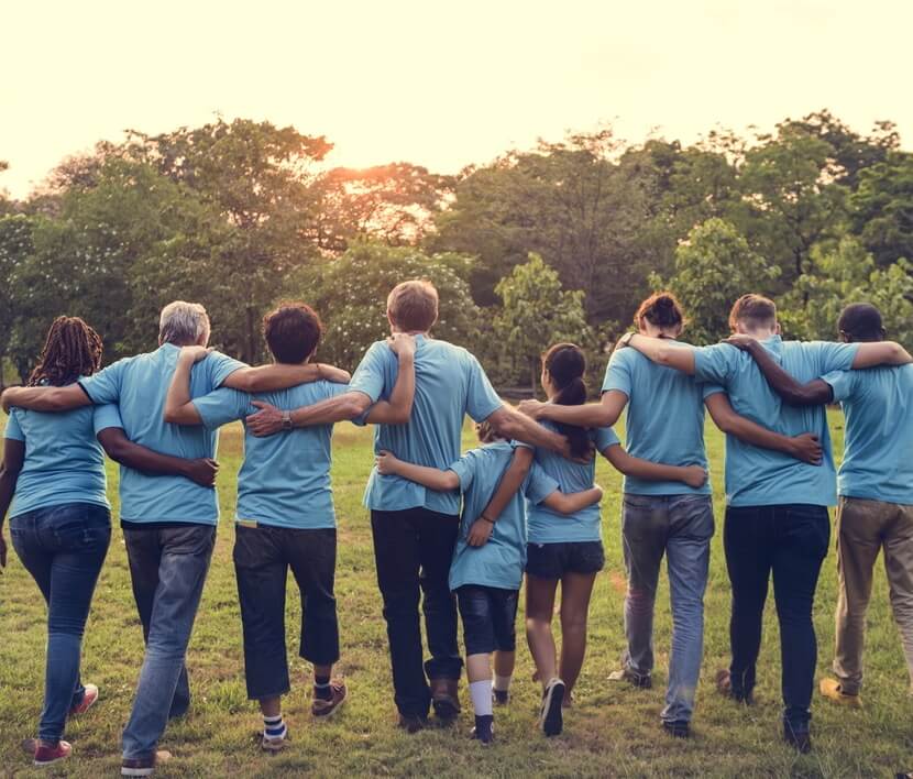 DAVACO team, all wearing blue shirts, walking in a green field.