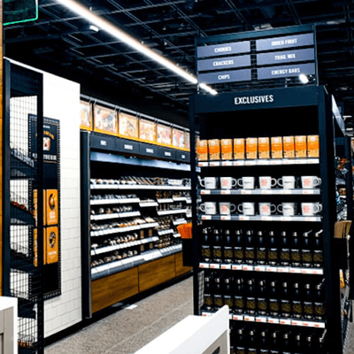 Black end cap of a store aisle inside Amazon Go, featuring white coffee mugs and bright orange coffee to match Amazon's color scheme.