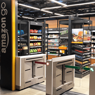 Bright grocery aisle inside Amazon Go, showing natural-colored food packaging for an eco-friendly feel, with bright beverages lining the side aisles.