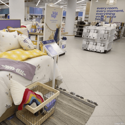 Purple, white and yellow comforter displayed on a bed in a Bed Bath & Beyond Store