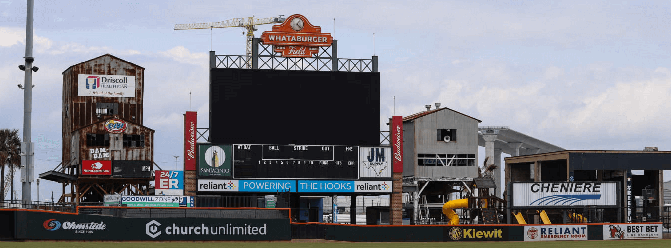 Scoreboard of the Corpus Christi Hooks at Whataburger Field. Colorful sponsorship signs surround a giant LCD screen for a baseball field.