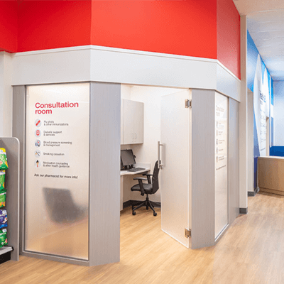 Entrance to a consultation room at a CVS Health location. The entrance is white and bright red, with light wood modern flooring.
