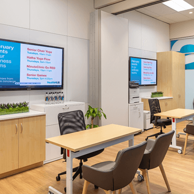 Light wood desk welcoming new patients at the care concierge desk at a CVS Health location. Walls are bright blue with painted white words HealthHub.