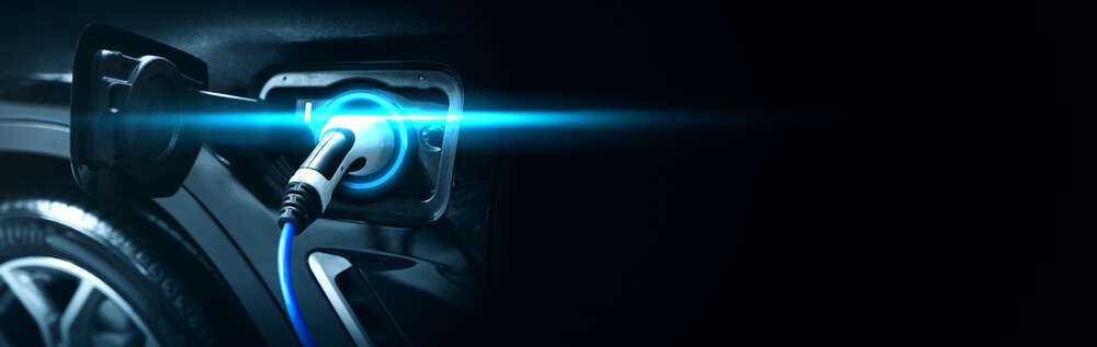 Black electric car being charged with a blue light, showing the power of EV charging by EOS Linx.