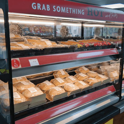 Red, countertop Flexeserve warmer with precooked sandwiches in brown paper and words reading 'Grab something hot' along the top of the case.