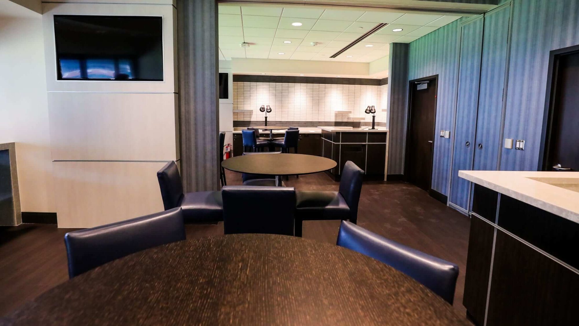 Interior of Bank of America Suite at the Houston Astros Stadium, showing modern, wood pub tables, blue walls and new wood flooring.