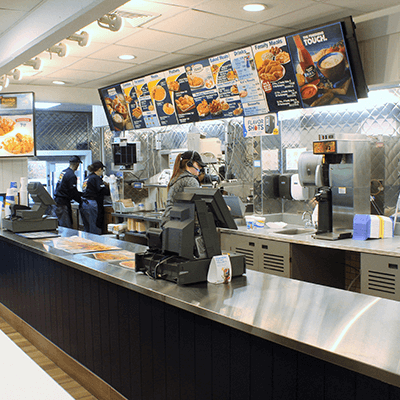 Front counter of a remodeled Long John Silver's Restaurant, with large LCD menu screens, metallic counters and employees hard at work.