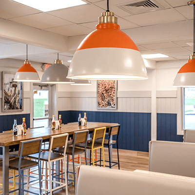 Dining area of a Long John Silver's restaurant, focusing on brightly colored orange lighting, with blue booths and rustic, wooden flooring.