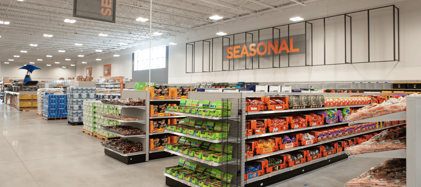 Newly remodeled Mills Fleet Farm store, showing orange 'Seasonal' sign with halloween candies stocked in food aisles with a warehouse design.