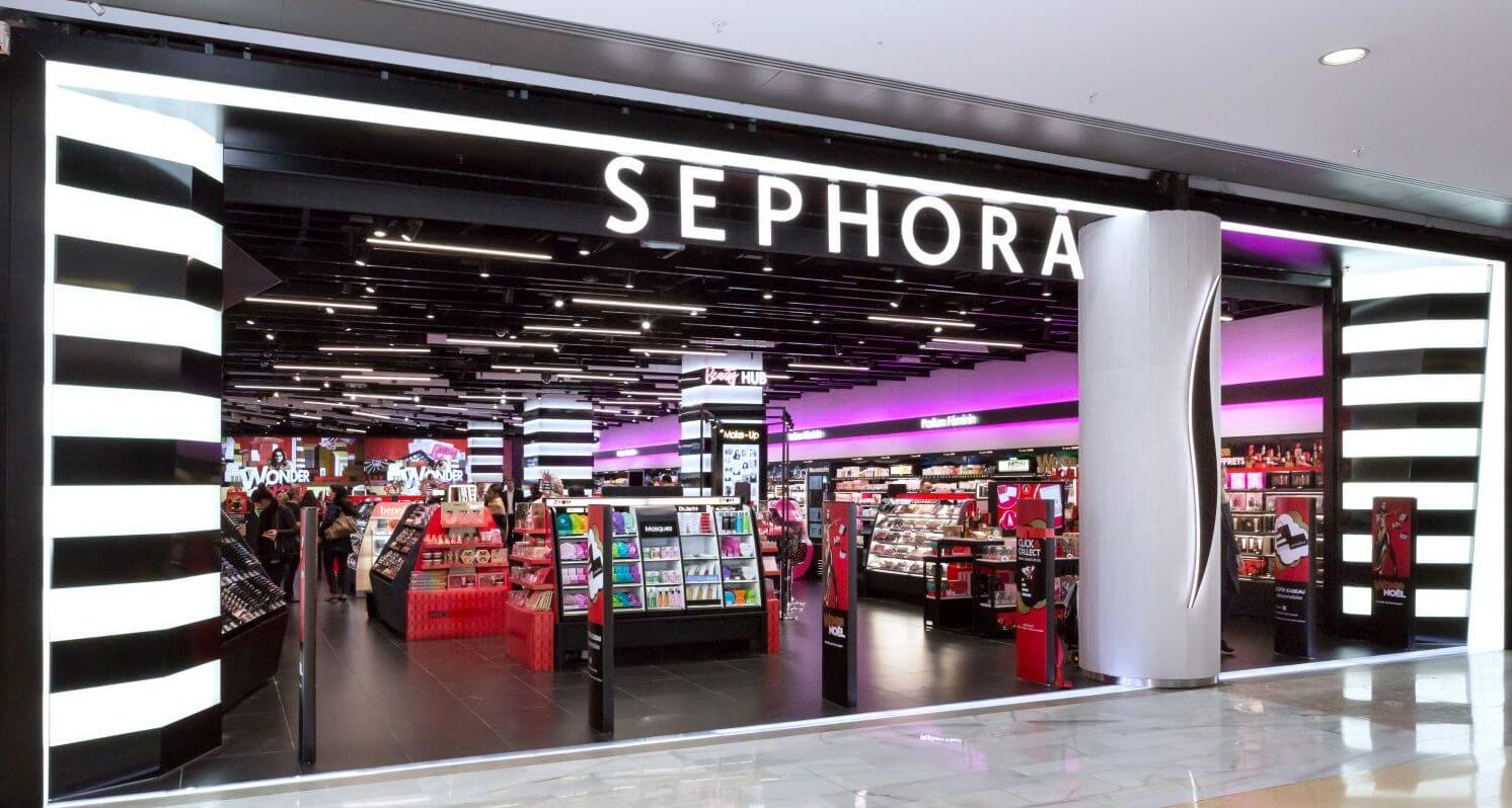 Front entrance of a newly remodeled Sephora cosmetics store, showcasing black and white striped columns and neon pink lighted displays.
