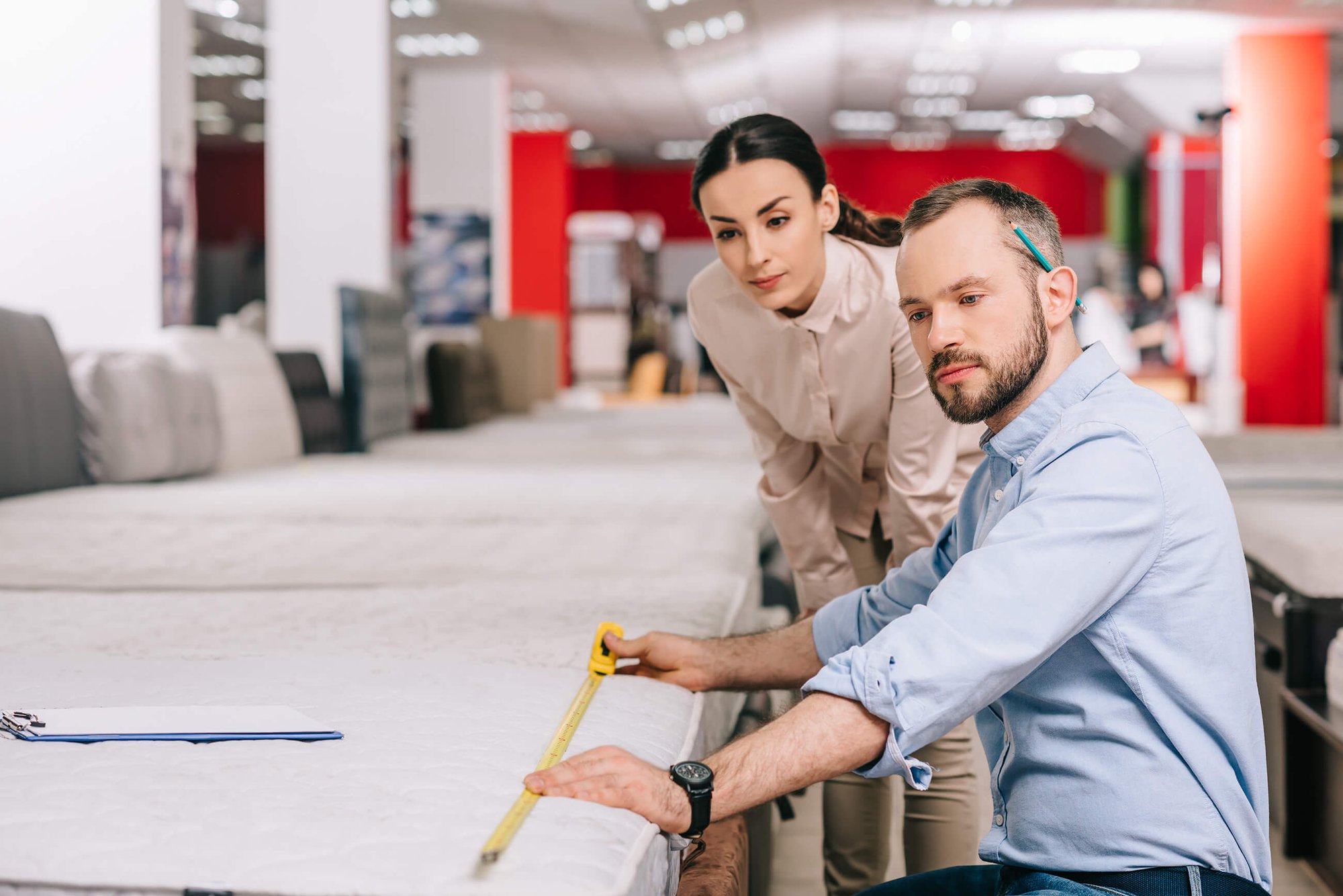Man wearing a blue business shirt, looking at architectural drawings with a brunette business woman wearing a white button shirt.