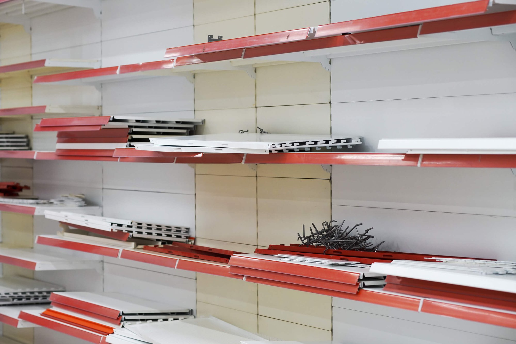 Multiple red and white metal shelving components inside of a retail store.
