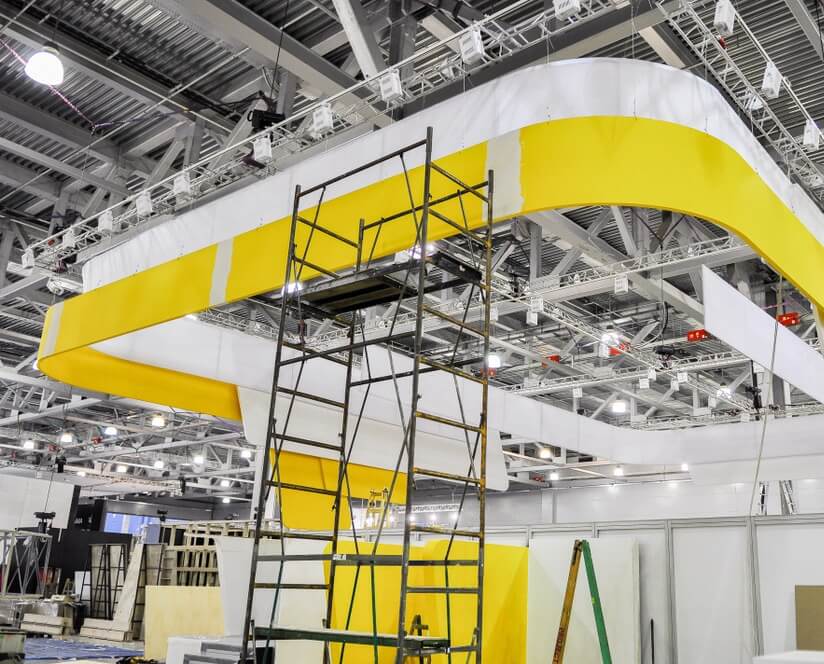 Metal scaffolding against a yellow and white horizontal banner at a corporate event site, showcasing DAVACO