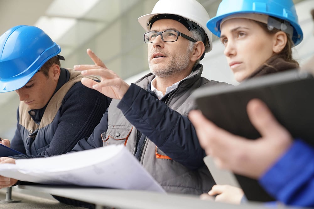 Three construction workers in vests and hard hats pointing at a job site with phrase 'What Happens Next' on top of the image.