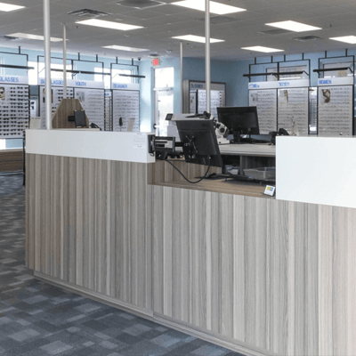 Patient welcome counter at a Stanton Optical My Eye Lab store, highlighting wood-paneled counters and a back wall featuring eyeglasses for sale.