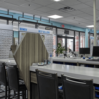 Interior of Stanton Optical My EyeLab store, focusing on white countertops, brown seats and walls of new eyeglasses for sale.