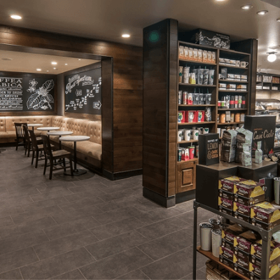 Dining area of a newly remodeled Starbucks coffee shop, featuring tan booths, wooden chairs and cabinets and earth-toned walls and flooring.