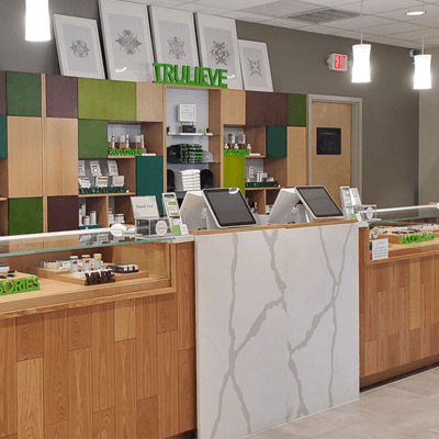 Checkout station at a Trulieve cannabis store. The register is surrounded in green block accents with white marble flooring and counters.