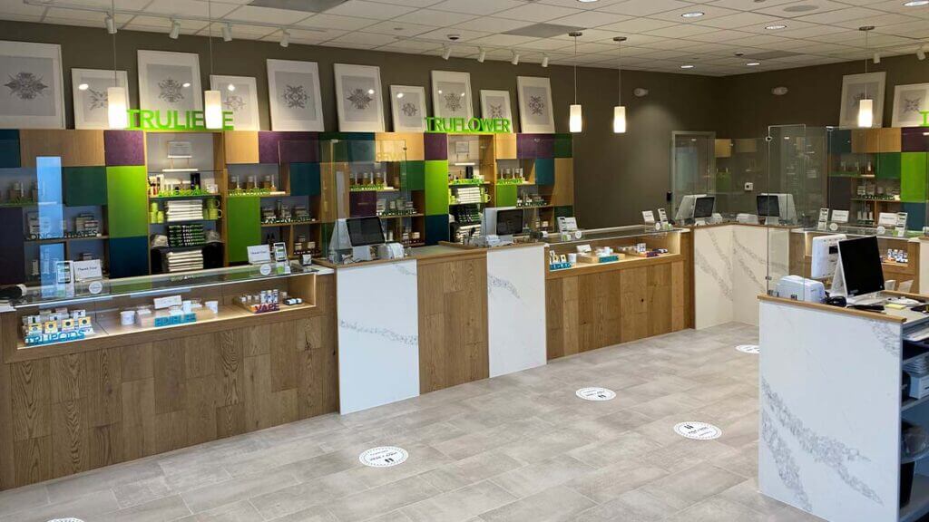 Interior checkout area of a Trulieve cannabis store. Each checkout has a marble front, is enclosed with glass and surrounded by wooden accents.